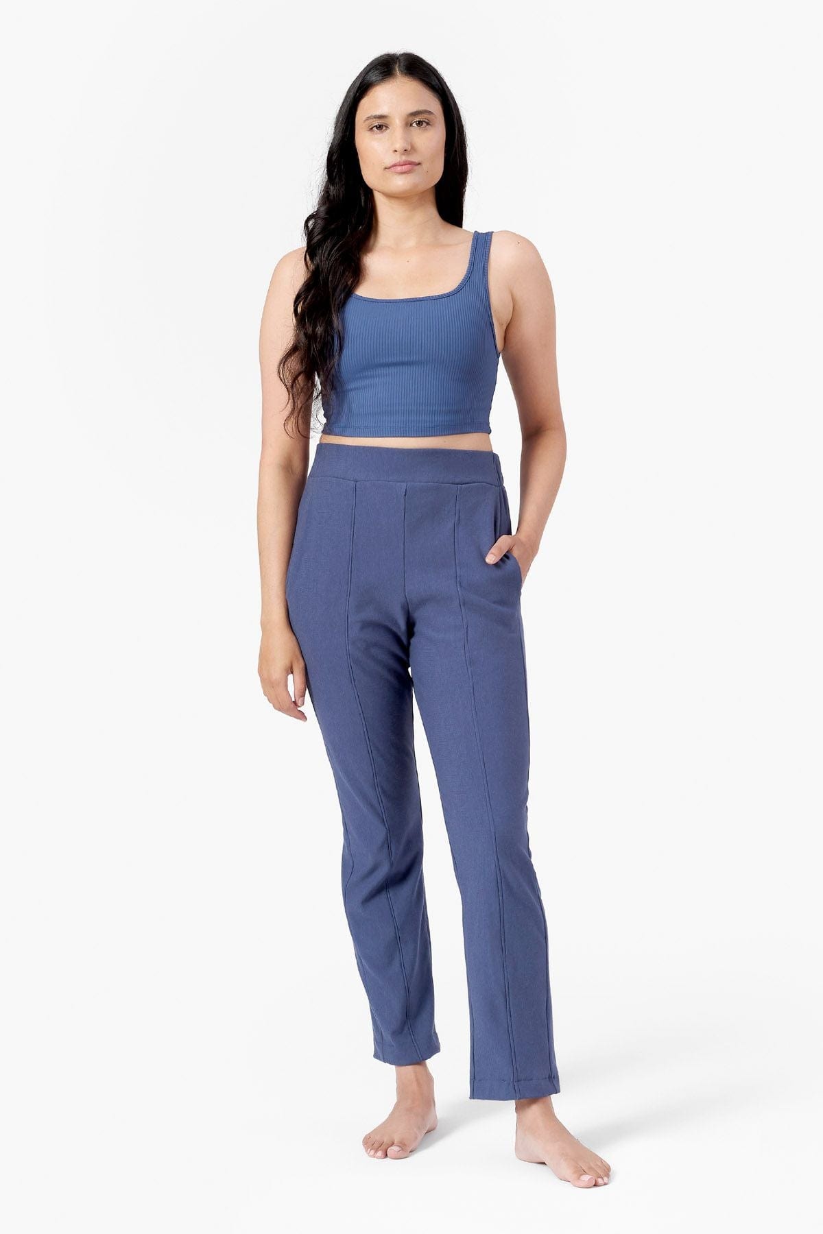 a woman wearing blue straight leg faux pleated pants with blue ribbed square neck tank top