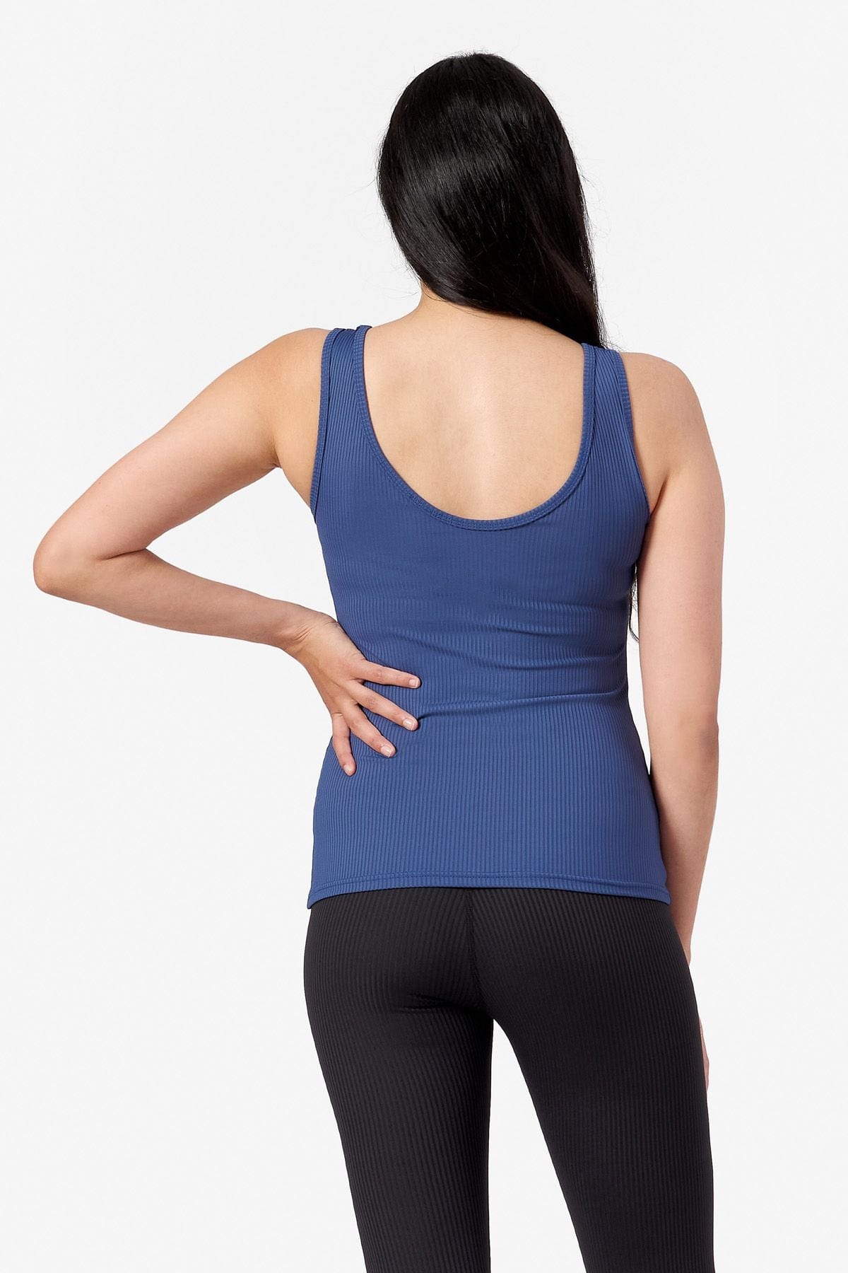 woman with hand on her hip wearing a blue full length tank top and black leggings