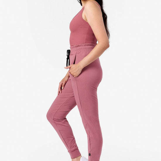 side view of a woman wearing pink joggers with pockets and a pink tank top