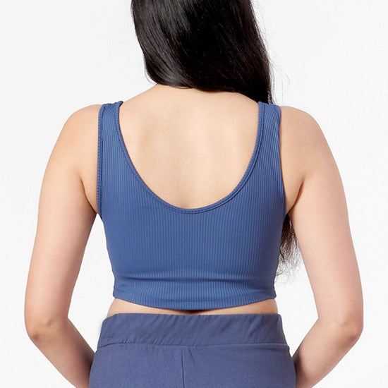 the back view of a woman wearing a blue crop top with a low scoop neck line