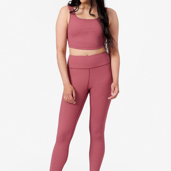 full length view of a woman wearing a matching pink ribbed yoga set with tank top and leggings