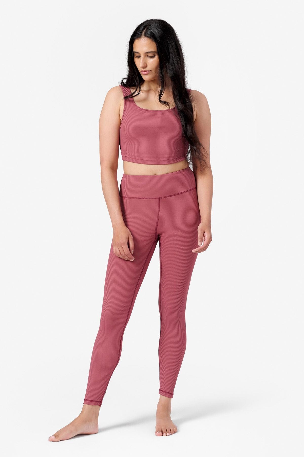 full length view of a woman wearing a matching pink ribbed yoga set with tank top and leggings
