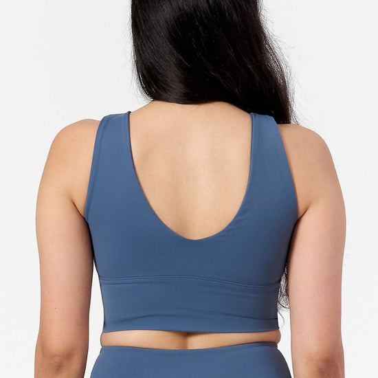 a woman wearing a low back reversible sports top in blue