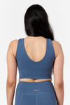 a woman wearing a low back reversible sports top in blue