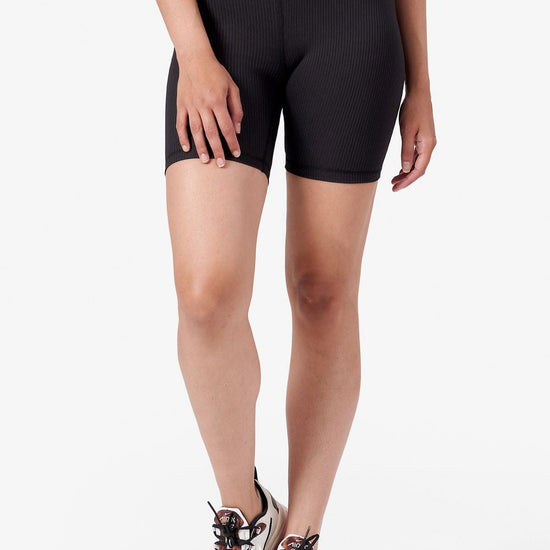 A woman modeling black ribbed bike shorts.