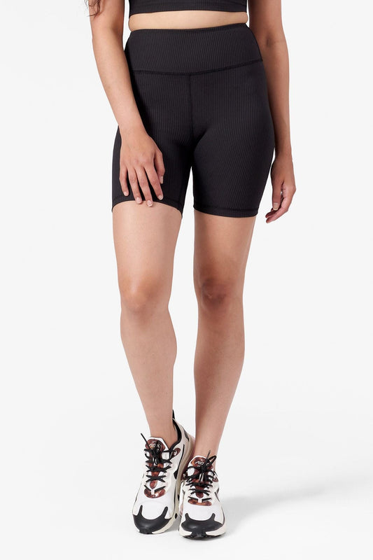 A woman modeling black ribbed bike shorts.