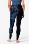 half view of a woman's legs from the back wearing blue and black tie dye leggings