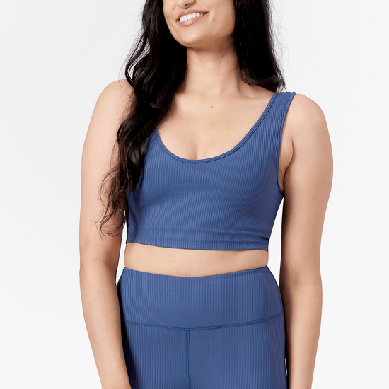 Woman wearing scoop side of a reversible ribbed sports bra in blue