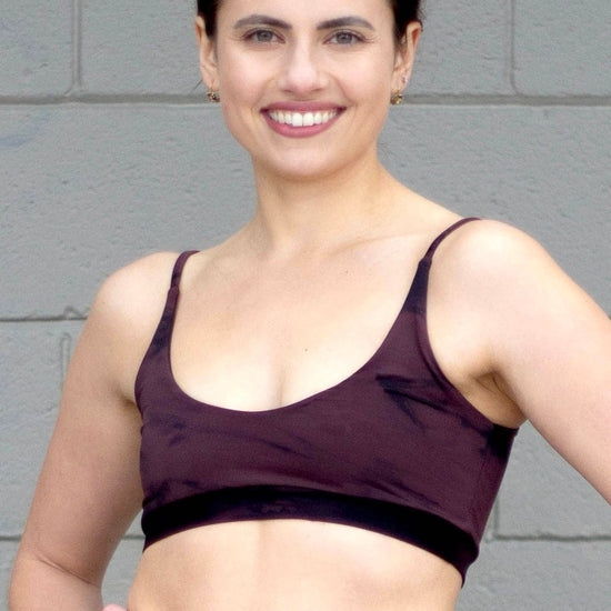 Woman wearing tie-dye swim top and black high-waisted swim bottoms