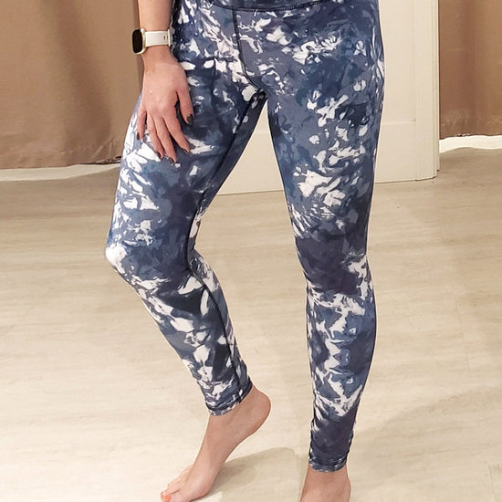 A woman wears a Fitbit, sports bra and pair of DAUB's limited edition Riley Leggings in a blue & white tie-dye print at DAUB's South Granville Flagship.