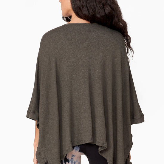The Back of a woman wearing a fine green knitted poncho
