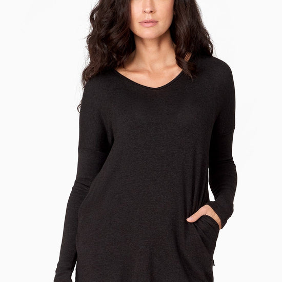 Woman wearing a long black knitted sweater with pockets.