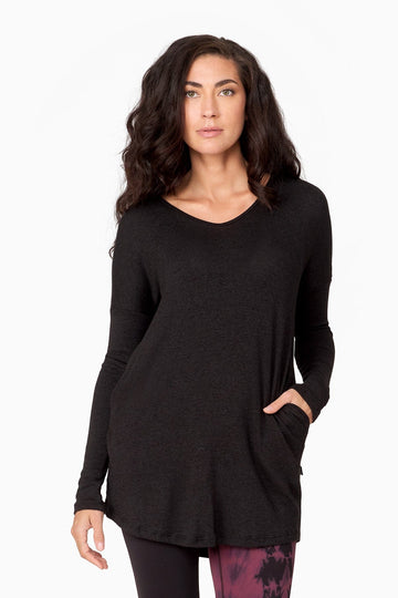Woman wearing a long black knitted sweater with pockets.