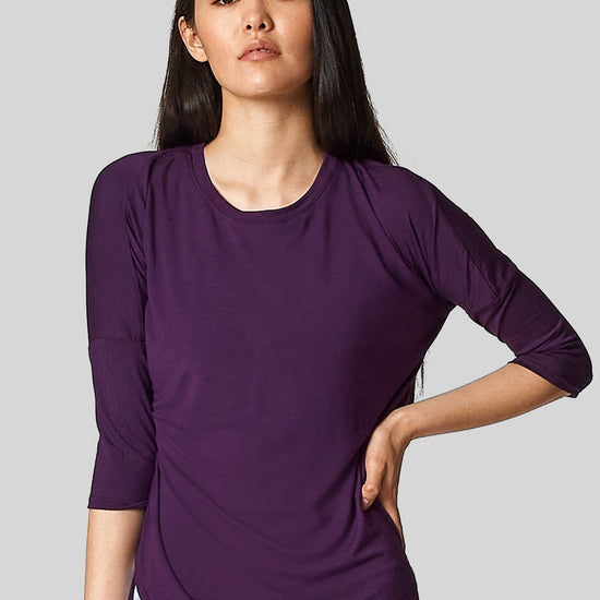 An asian female is wearing a purple t-shirt with 3/4 length sleeves.