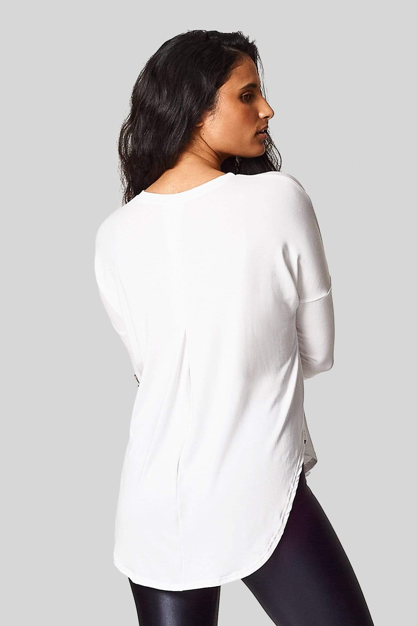 A brunette shows us the back pleat in her white 3/4 length sleeve tee-shirt.