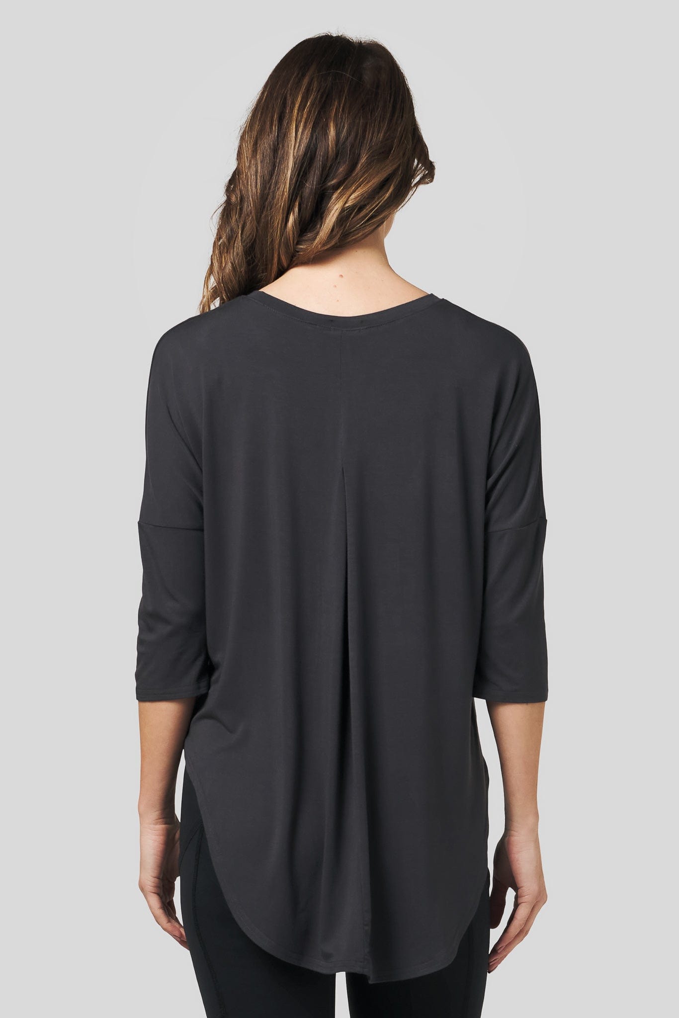 Back of a woman wearing a dark grey 3/4 length sleeve shirt