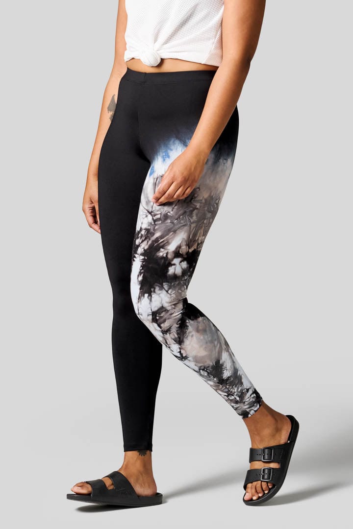 Side of a women wearing tie-dye leggings and black freedom  moses.