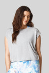 A brunette wears a light heather grey box tee with printed blue & white leggings