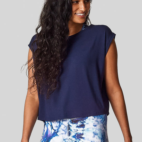 A brunette wears a navy colored box tee with matching printed leggings.