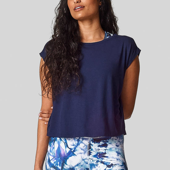 A brunette is wearing  a navy marine box tee with an exclusive printed legging.