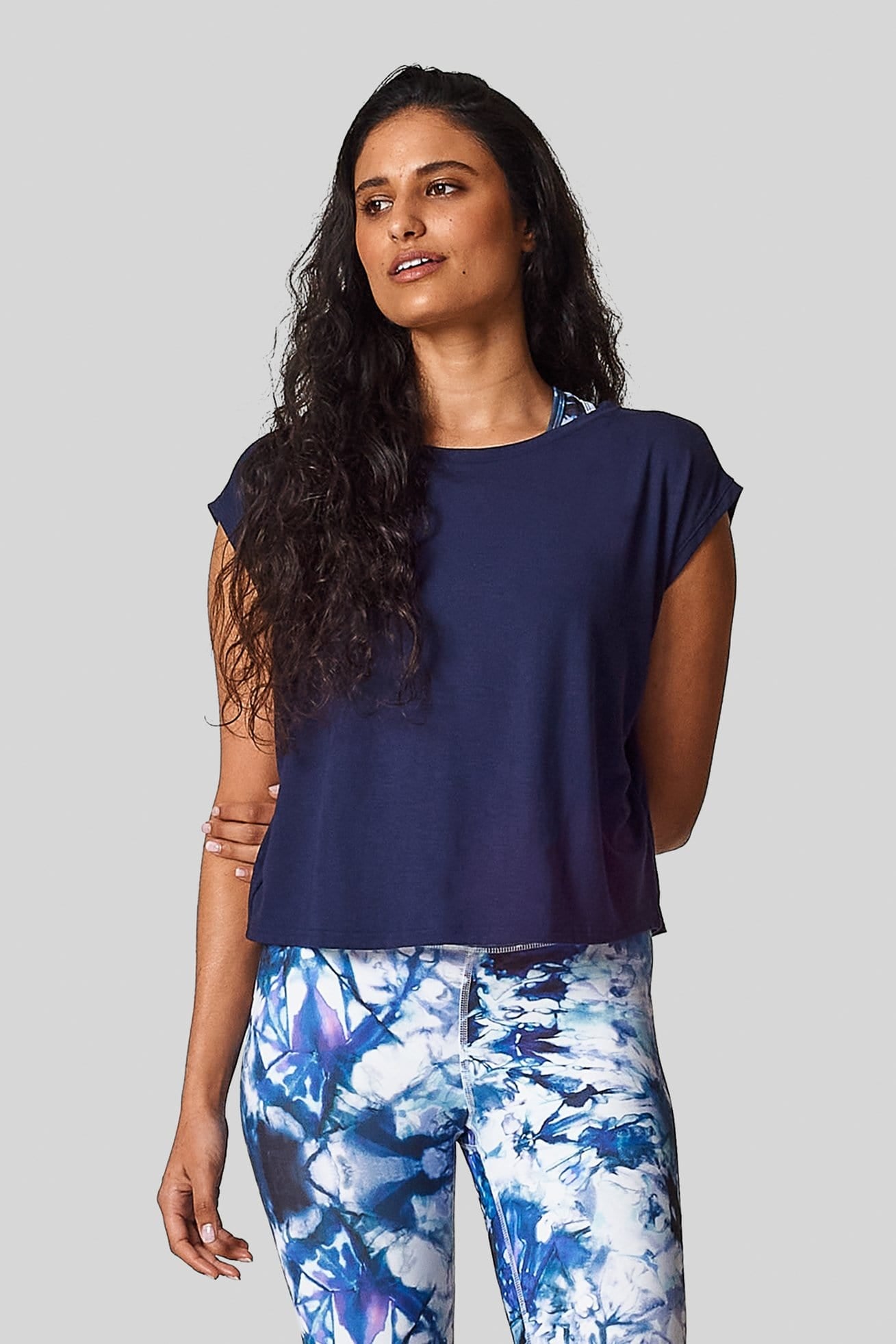 A brunette is wearing  a navy marine box tee with an exclusive printed legging.