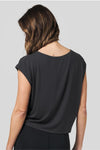Back of a women wearing a dark grey loose fit sleeveless tee and black legging.
