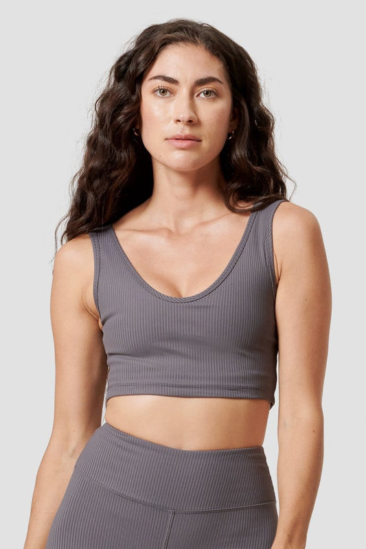 A woman modeling a grey ribbed sports bra with a scoop neck.