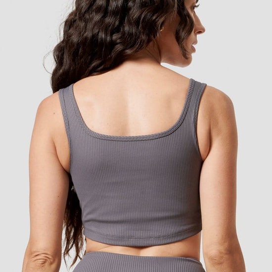 A brunette model models a grey ribbed sports bra.