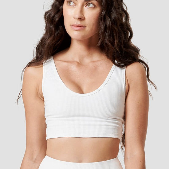 A woman wearing a white scoop-neck sports bra.