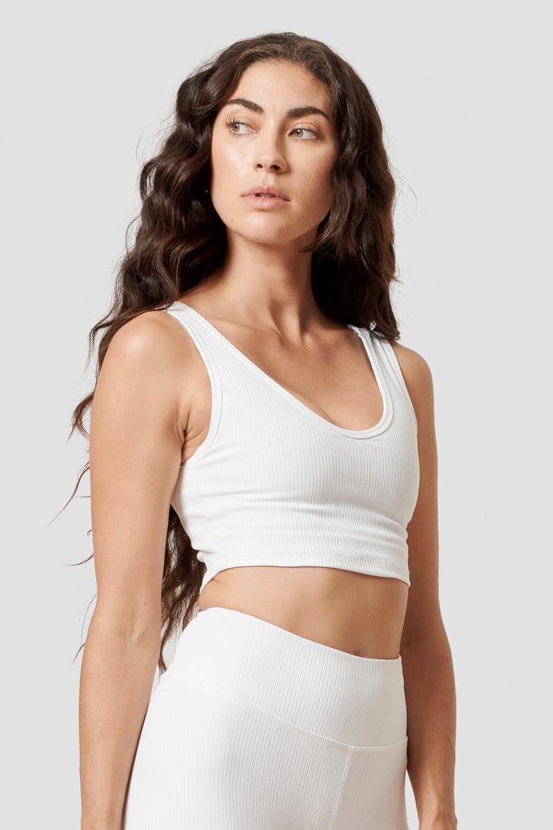A woman looking over her shoulder modeling a white reversible top. 