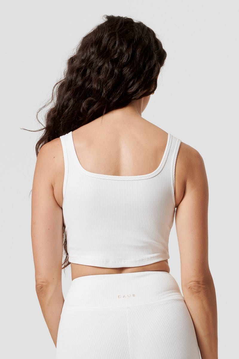 A woman faced back wearing a white ribbed reversible sports bra. 