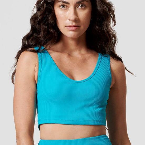 A woman wears a teal ribbed sports bra with a scoop-neck.