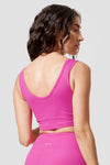 A woman wearing a hot pink reversible top looks over her shoulder.