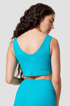 A woman looking over her shoulder models the back of a bright blue ribbed sports bra. 