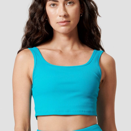 A woman models a teal reversible sports bra.