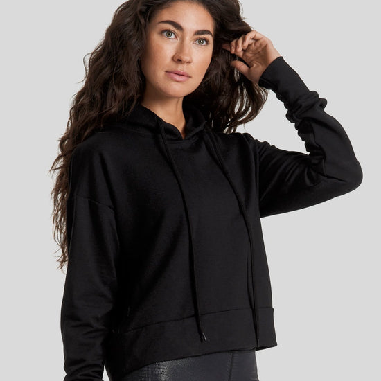 A woman wearing an all black hoodie and shiny textured leggings