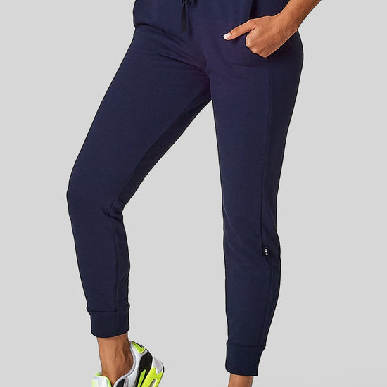 A woman wears a navy jogging pant with pockets and a drawstring.
