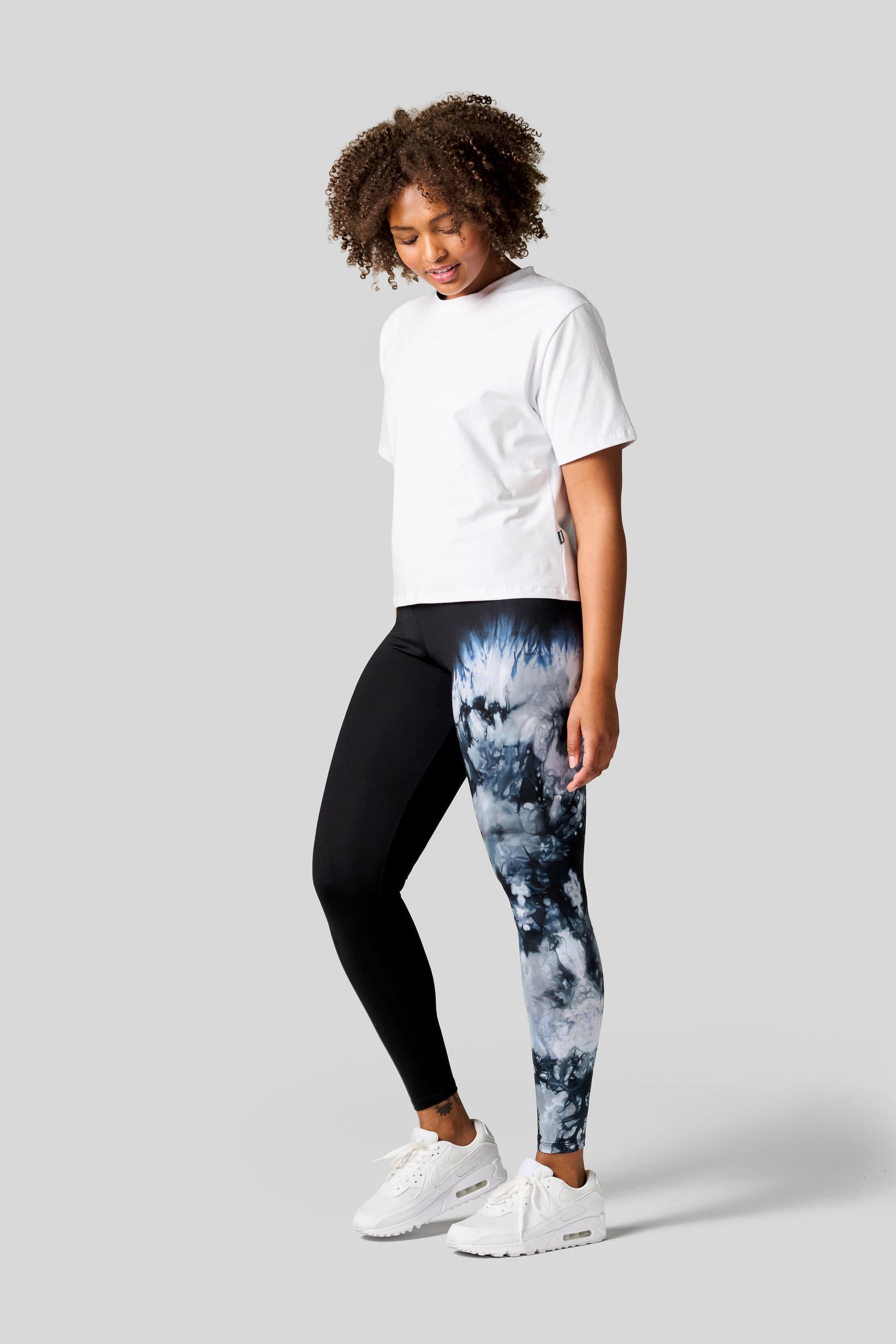 Woman wearing a white tee with one leg tie dye leggings and Nike Air Max shoes