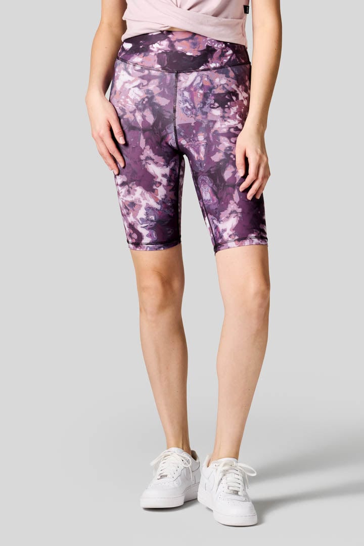 Women wearing tie dye bike shorts with a lavender tank and Nike shoes