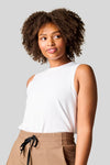 Women wearing a high neck white tank top tucked in brown wide leg pants,