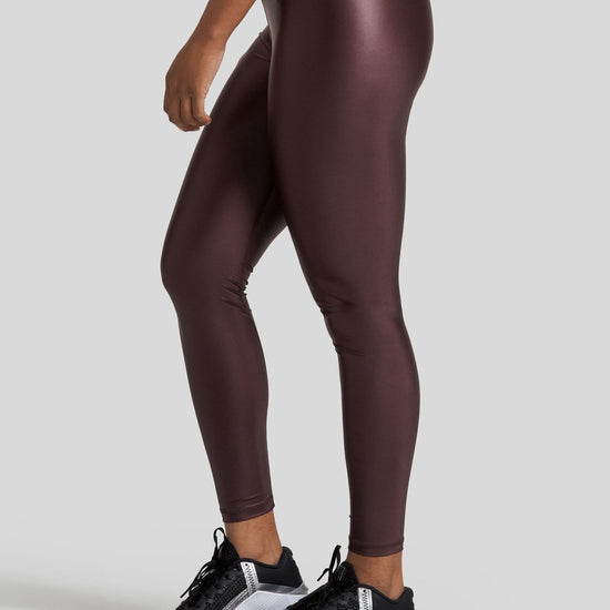 The side profile of a woman's legs are shown wearing hi gloss brown leggings