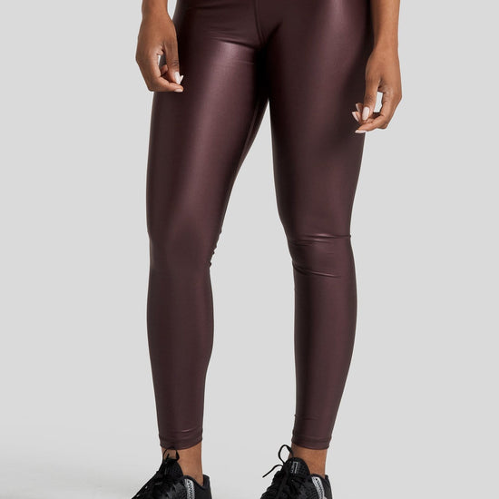 A woman's legs are shown wearing shiny brown leggings