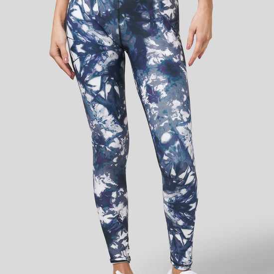A woman models a pair of crisp white sneakers paired with a pair of blue leggings in a tie-dye print.