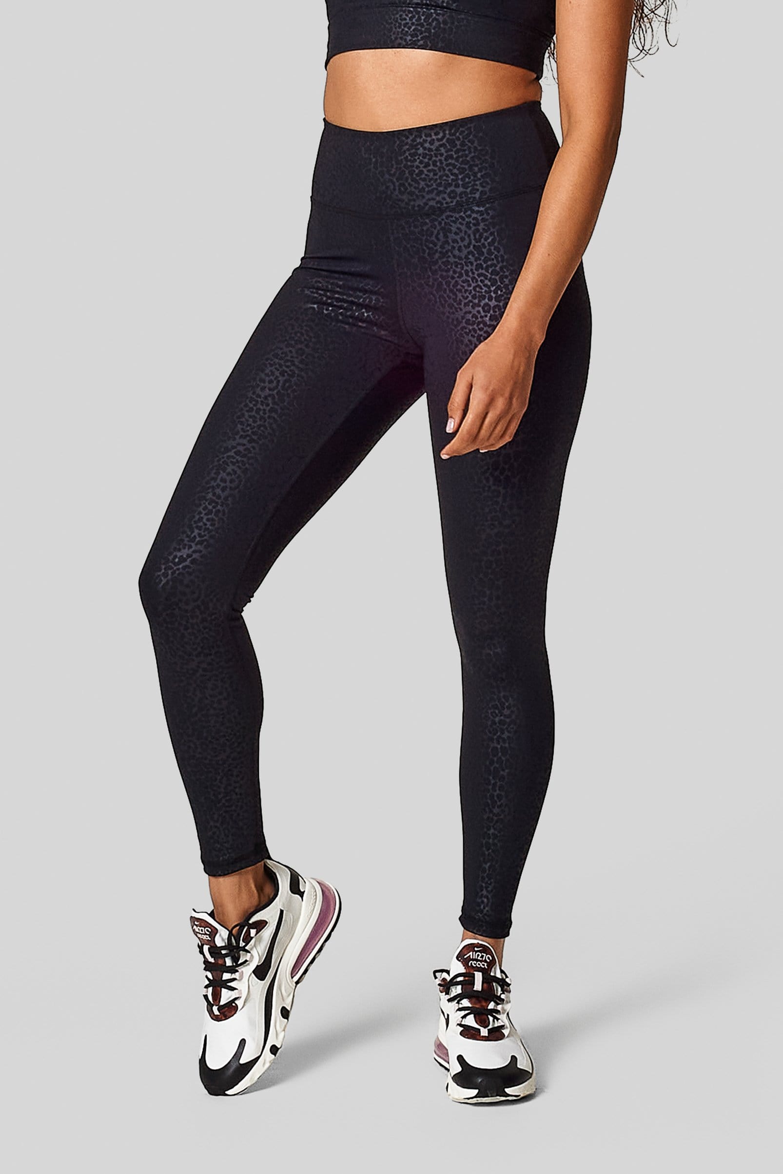 A woman wears new nikes with a pair of black Cheetah print high waisted leggings.