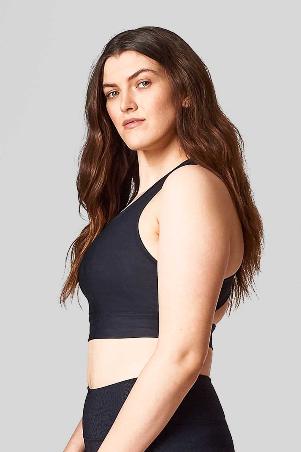 Side view of a woman wearing a black sports bra.