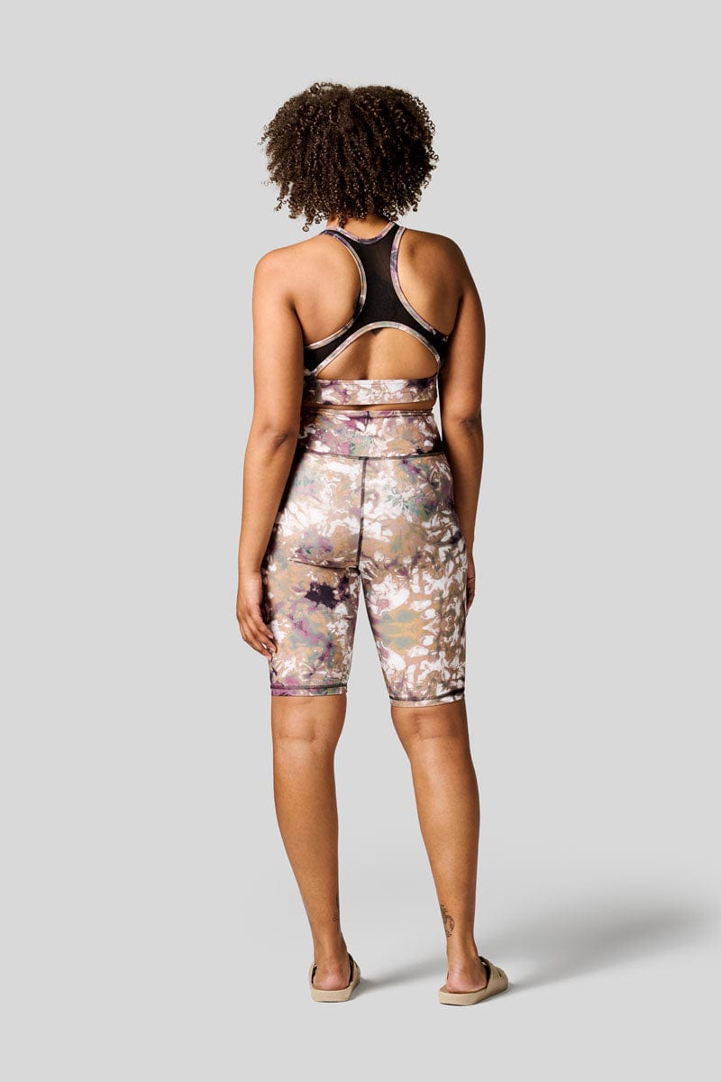 Back of a women wearing brown tie dye bike shorts with matching sports bra and Freedom Moses