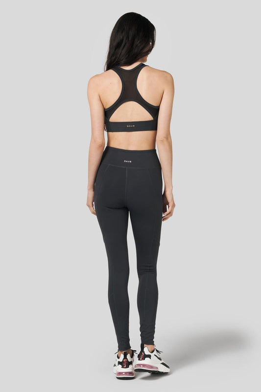 Back of a women wearing charcoal leggings and matching sports bra with Nike shoes