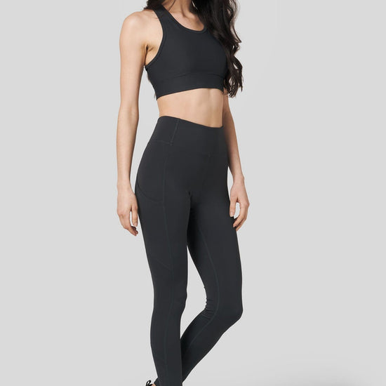 Women wearing charcoal leggings and matching sports bra with Nike shoes 