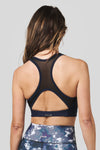 Back of a women wearing a navy sports bra and tie-dye printed legging