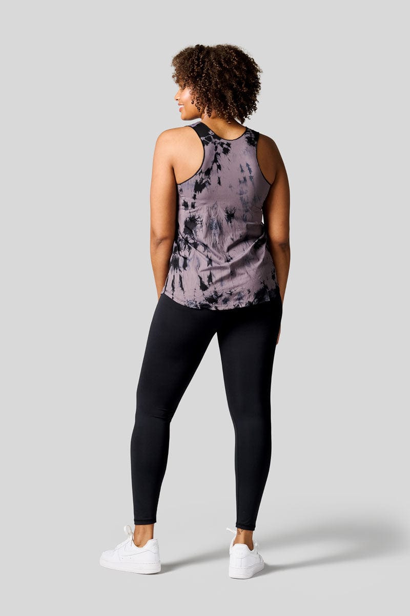 Back of a women wearing a tie dye tank top, black leggings and Nike Air Force shoes
